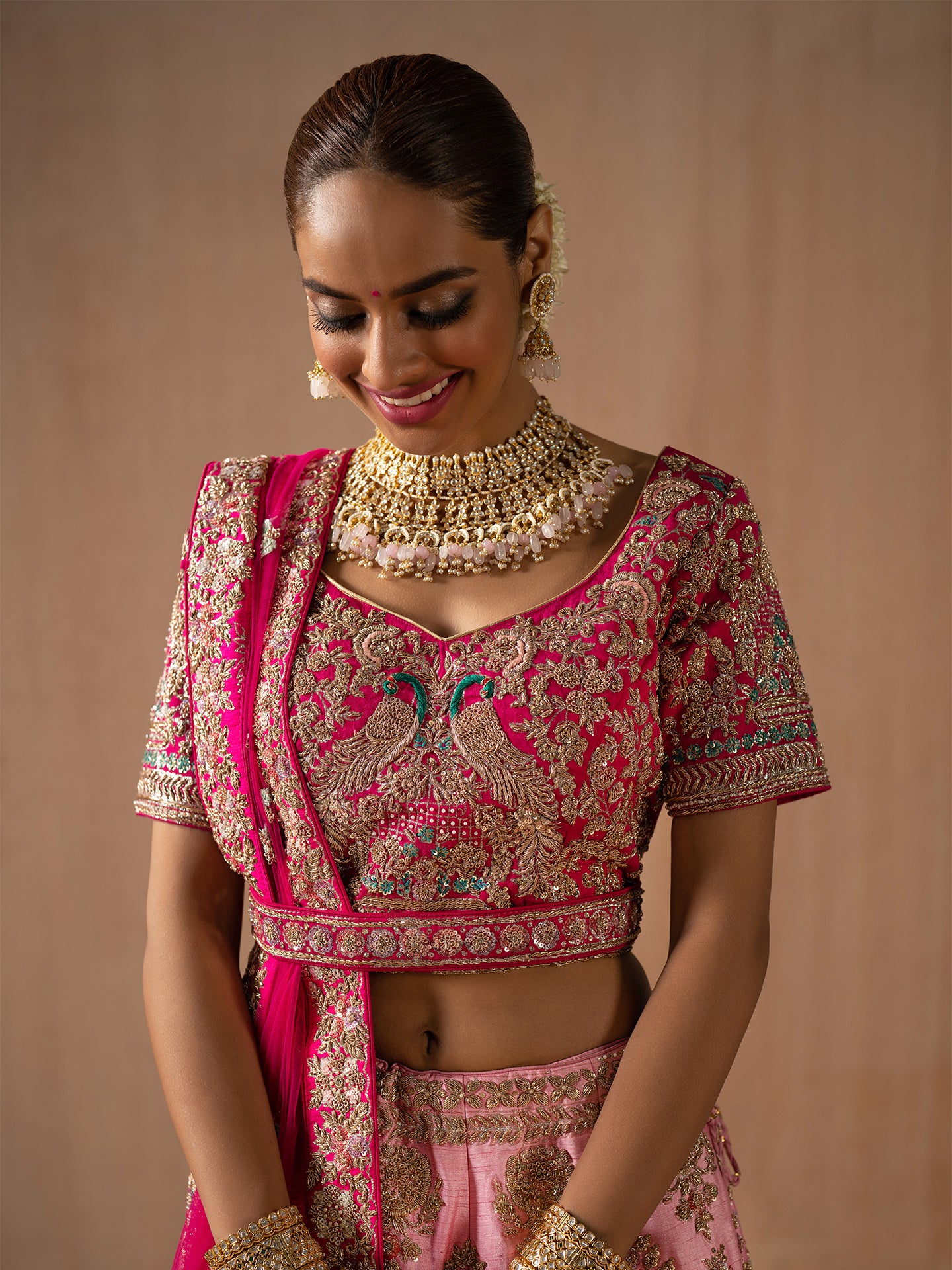 Luxurious pink lehenga in silk with golden dabka work.