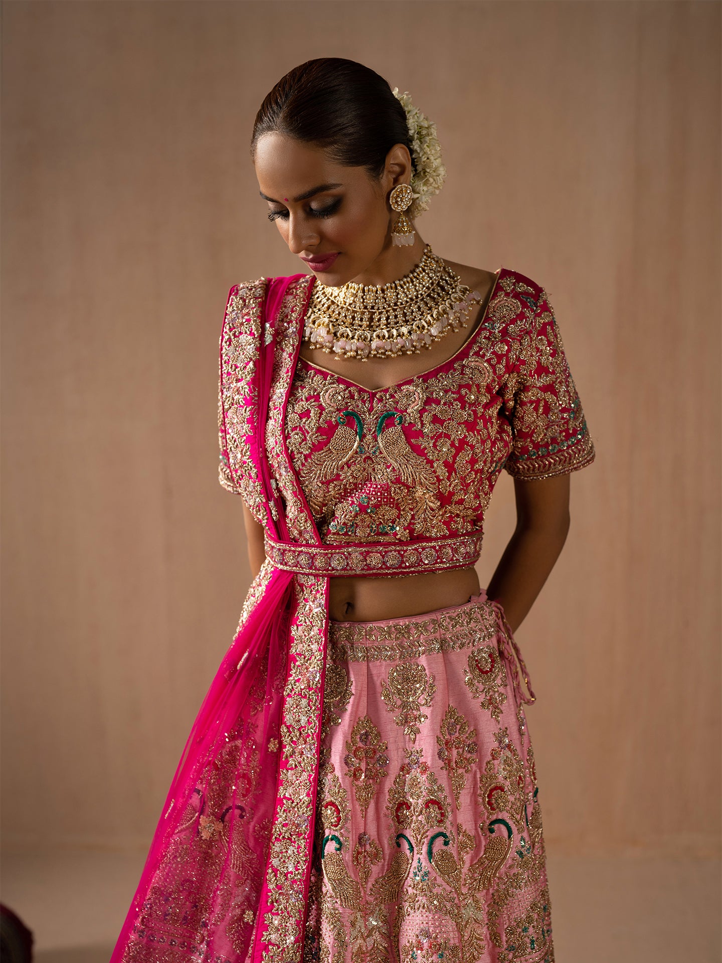 Luxurious pink lehenga in silk with golden dabka work.