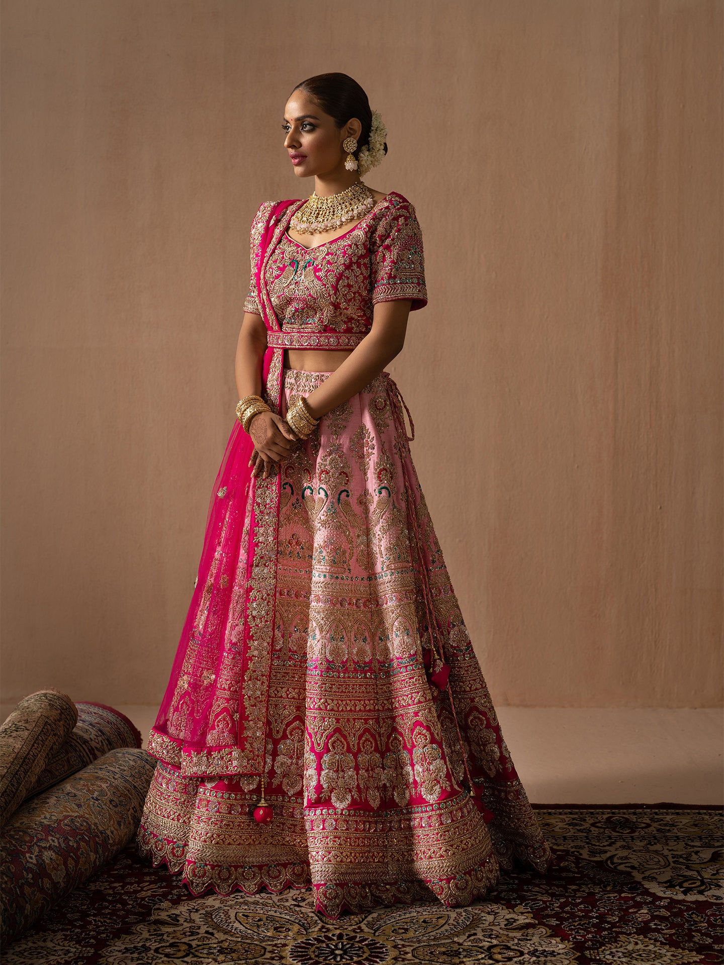 Luxurious pink lehenga in silk with golden dabka work.